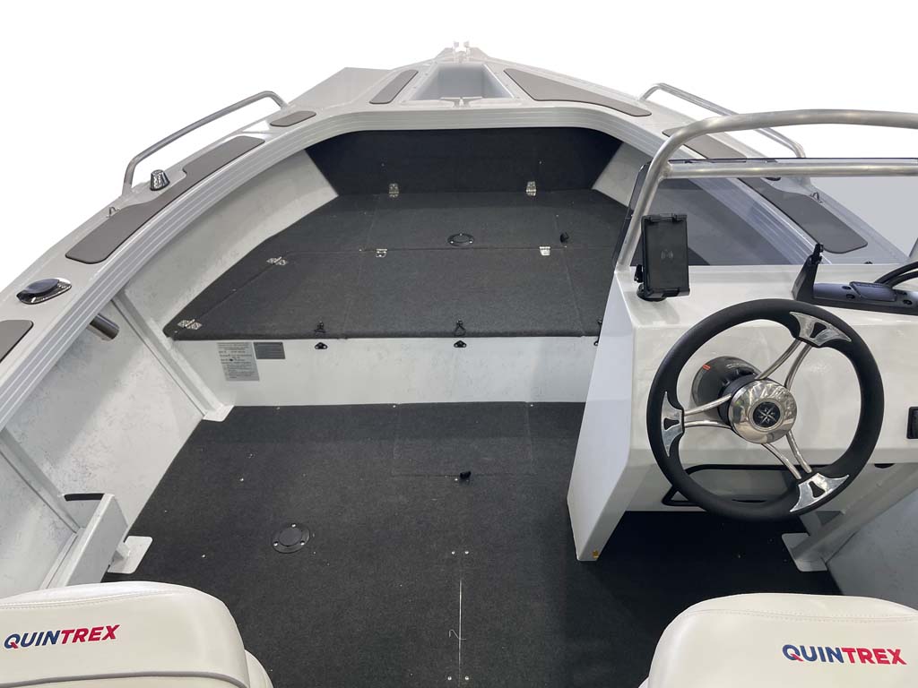 Interior view of a Quintrex boat featuring a carpeted deck, steering wheel, console, and forward casting platform.