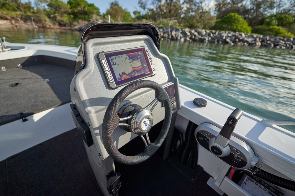 Interior view of a Quintrex boat console with a steering wheel and Lowrance fish finder.